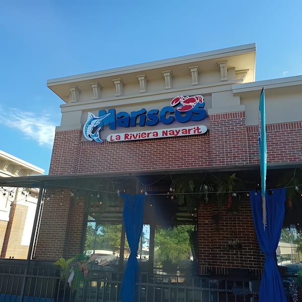 The exterior of Mariscos La Riviera Nayarit, a seafood restaurant, with its blue and red sign.