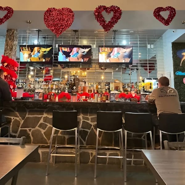 A bar at Mariscos La Riviera Nayarit with red heart decorations, TVs, and patrons.