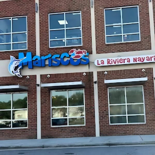 Exterior of Mariscos La Riviera Nayarit restaurant, with blue signage and a brick facade.