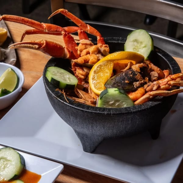 Seafood molcajete with crab legs, shrimp, mussels, orange, and cucumber slices.