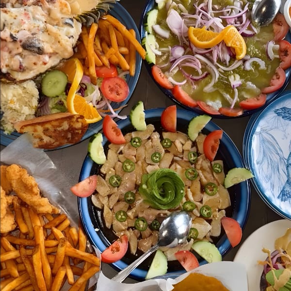 Overhead view of various seafood dishes, including ceviche, fried fish, and a creamy lobster dish.